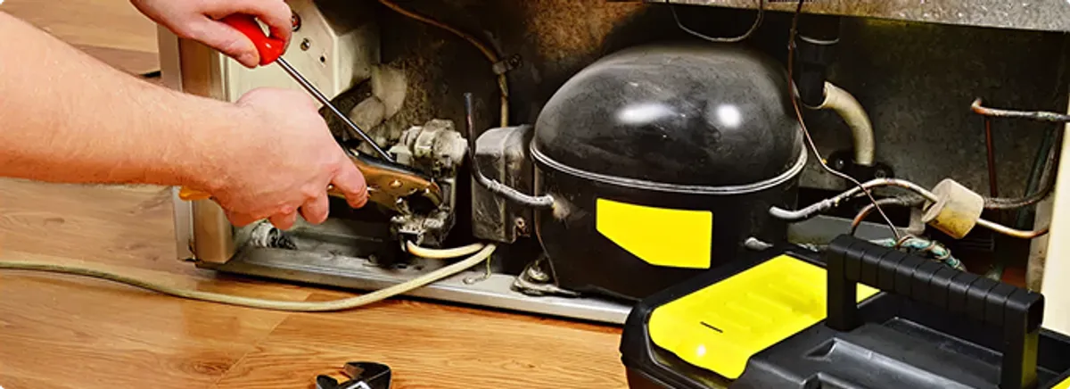 Refrigerator repair technician fixing the compressor and wiring in Brandon, FL