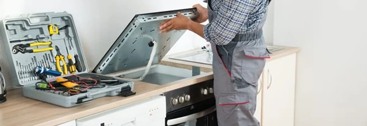 Cooktop repair technician lifting a built-in stovetop for service in Tampa, FL
