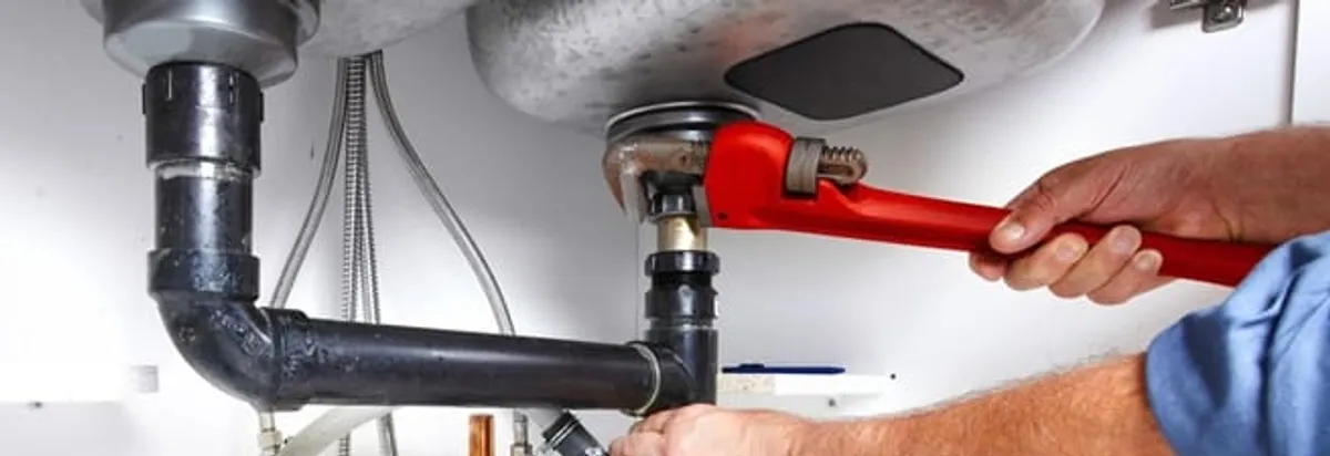 Garbage disposal repair technician tightening the sink drain and disposal connection in Tampa, FL