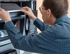 Appliance repair technician replacing a microwave vent filter in Tampa, FL