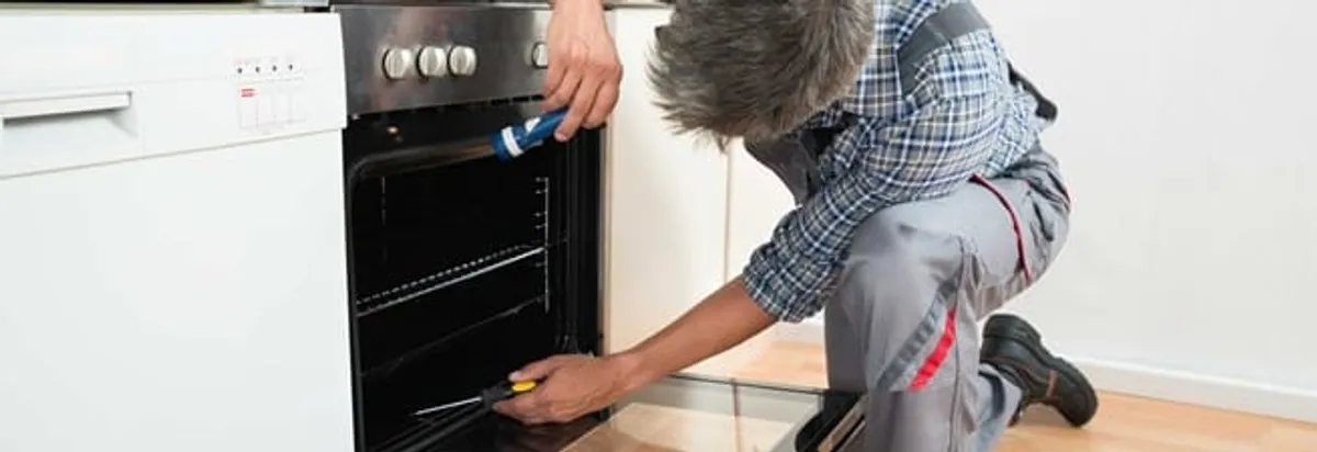 Oven repair technician inspecting and servicing an electric oven in Tampa, FL