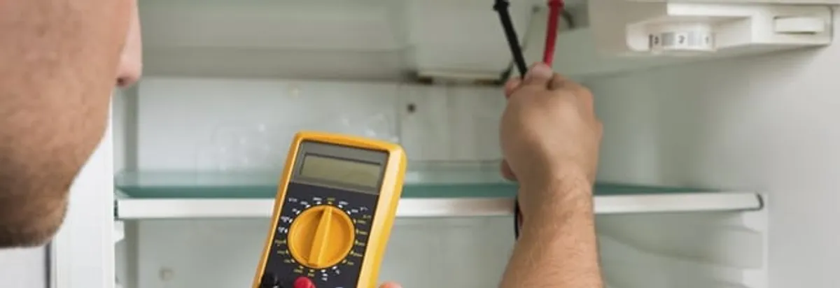 Refrigerator repair technician testing electrical components with a multimeter in Tampa, FL